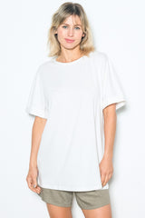 woman wearing a white oversized t-shirt with rolled short sleeves and light brown shorts