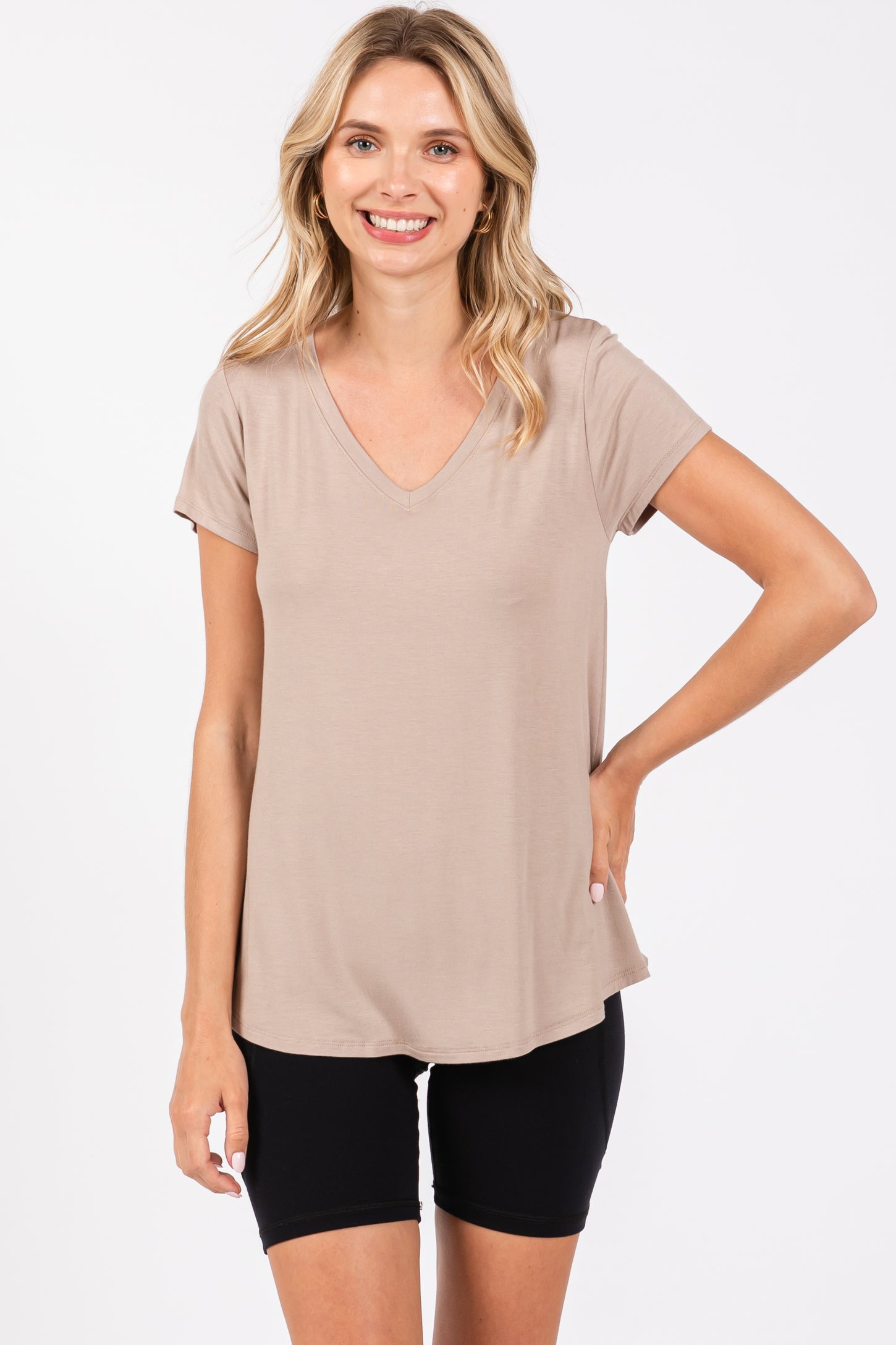woman wearing a beige v-neck t-shirt paired with black bike shorts, smiling at the camera