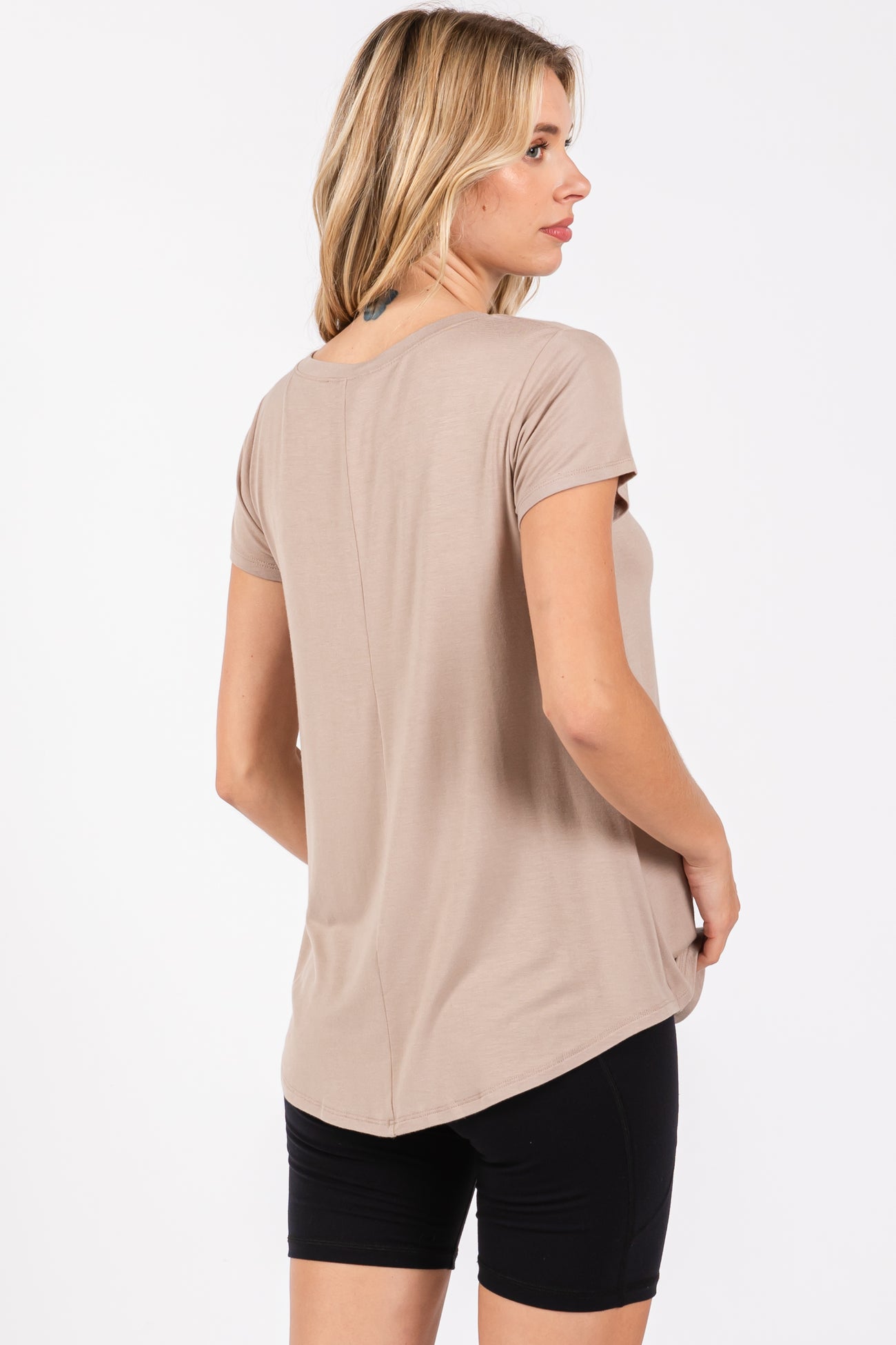 woman wearing a taupe short sleeve top, shown from the back, paired with black shorts