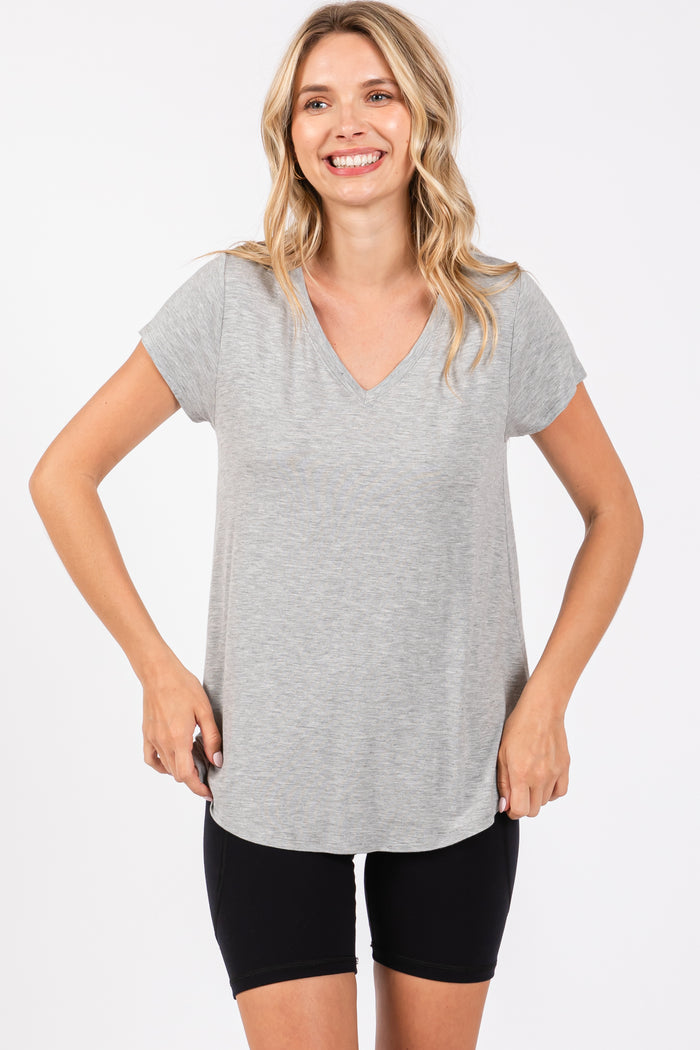 woman wearing a light gray v-neck t-shirt and black bike shorts, smiling at the camera