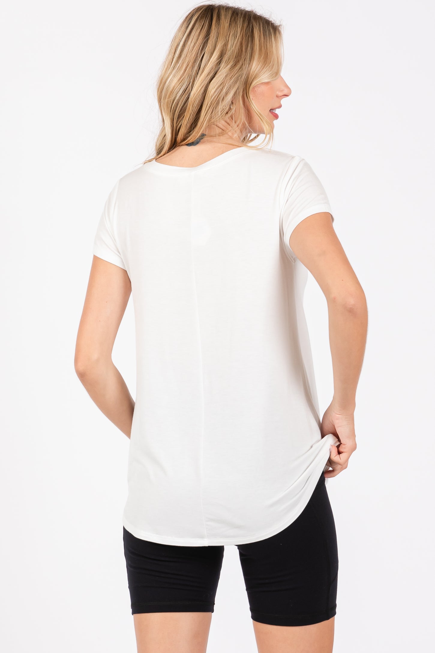 woman wearing a white short sleeve top and black shorts, shown from the back with a relaxed fit