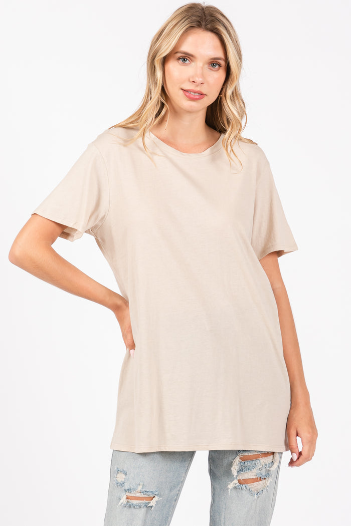 woman wearing a light beige oversized t-shirt with short sleeves and a relaxed fit, paired with distressed jeans