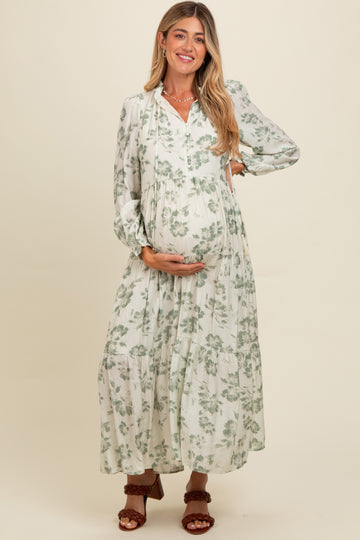 woman wearing a white floral maternity maxi dress and holding her baby bump
