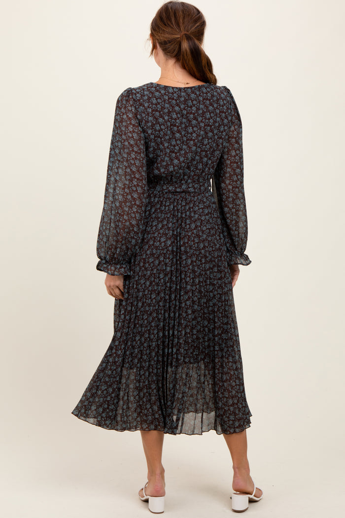 woman wearing a dark floral long sleeve midi dress with a pleated skirt and a cinched waist, viewed from the back