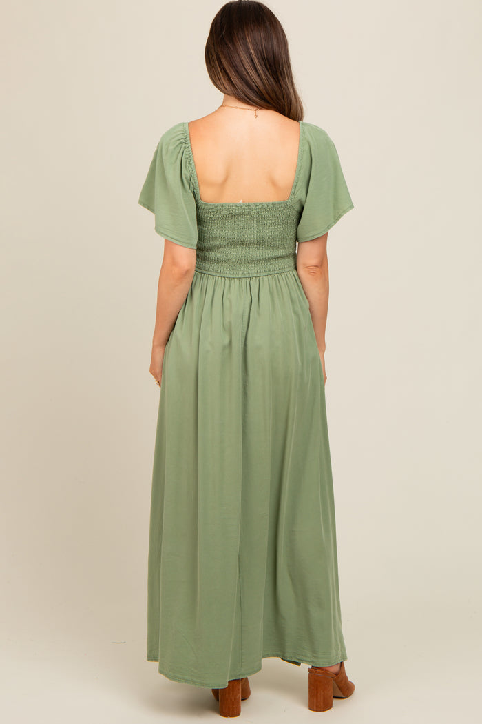 woman wearing a green maternity maxi dress with a smocked bodice and flutter sleeves, view from the back