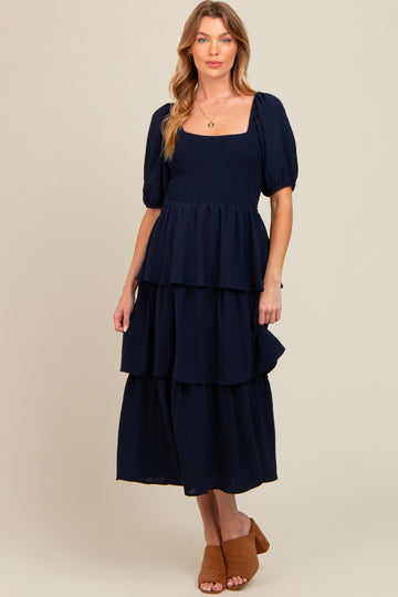 woman wearing a navy blue maternity tiered maxi dress with puff sleeves and a square neckline