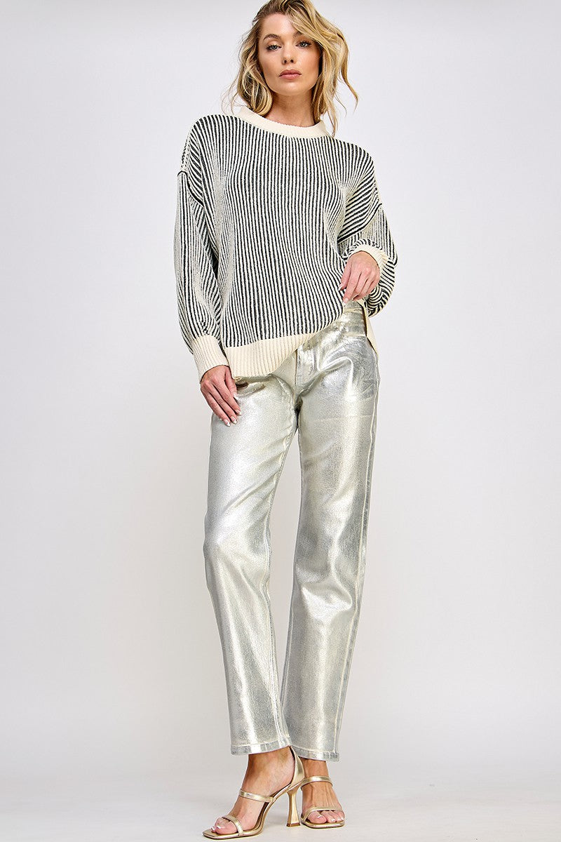 woman wearing a striped oversized sweater and shiny silver wide-leg pants with strappy heels