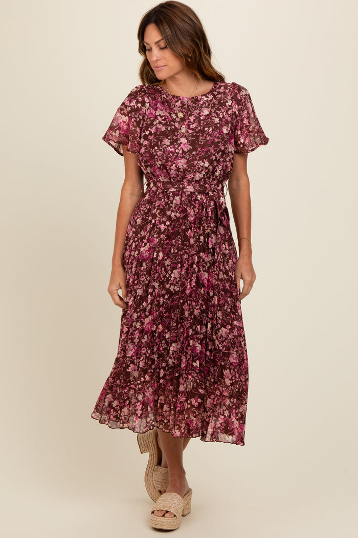 woman wearing a burgundy floral midi dress with short sleeves and a tie waist, standing and smiling