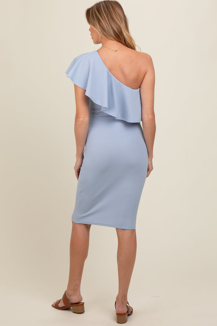woman wearing a light blue one-shoulder ruffled maternity dress, showing her back and the fitted silhouette