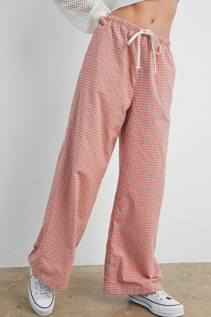 woman wearing plaid peach wide-leg pants with an elastic waistband and drawstring, paired with white sneakers