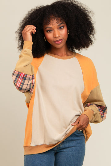 woman wearing a multicolored sweatshirt with plaid sleeves and a beige body, styled casually with denim jeans
