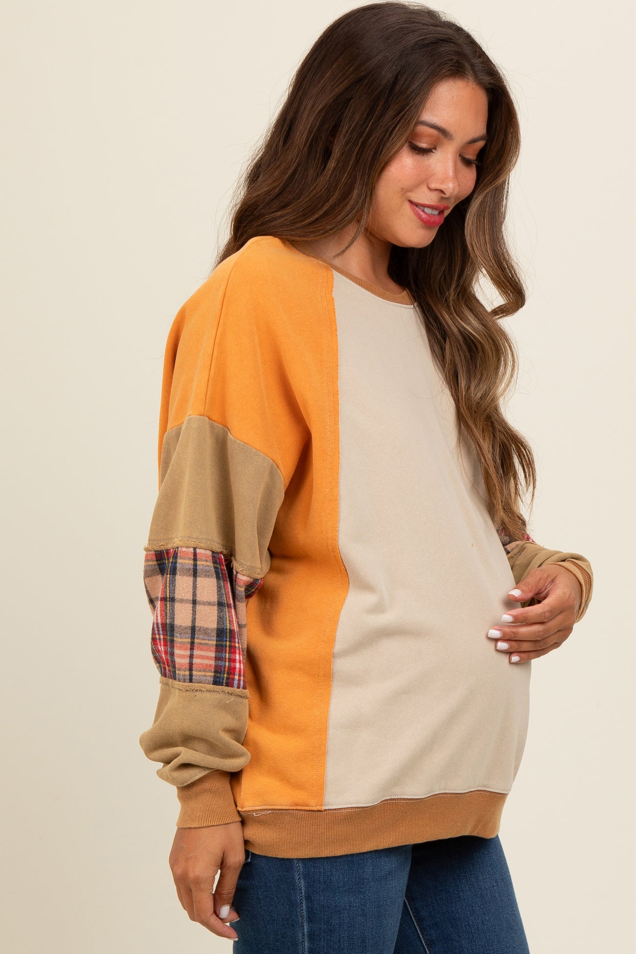 woman wearing a colorblock maternity sweatshirt with plaid sleeves and a visible baby bump