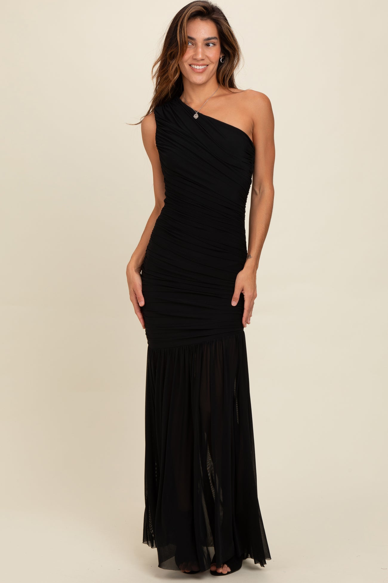 woman wearing a black one-shoulder evening gown with ruching and a flowing skirt
