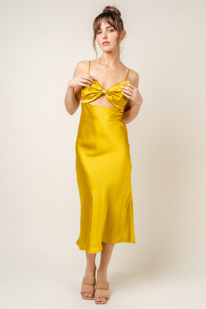 woman wearing a yellow satin midi dress with a bow detail and spaghetti straps