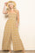 woman wearing a floral print strapless jumpsuit in mustard yellow with pockets and straw hat