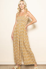 woman wearing a floral yellow maxi dress with smocked bodice and wide legs, posing against a neutral background