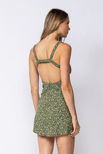 woman wearing a green floral mini dress with a scoop back and adjustable straps