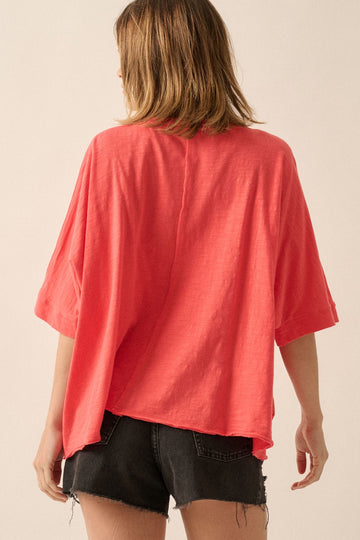 woman wearing a coral oversized t-shirt with short sleeves and a loose fit, paired with black shorts