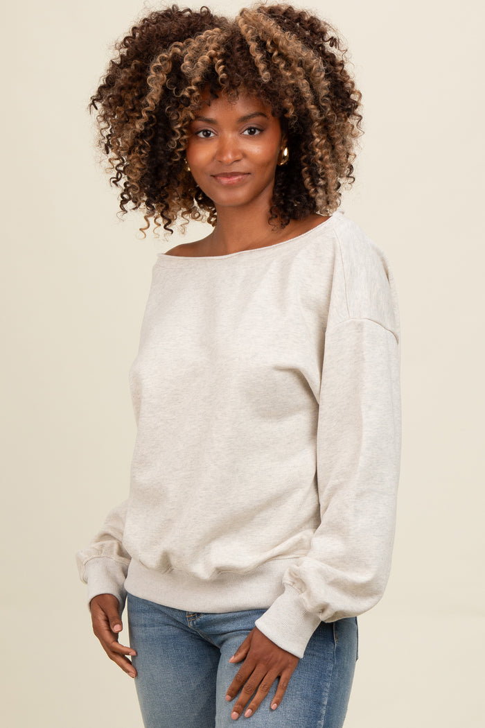 woman wearing a light beige off-the-shoulder sweater with balloon sleeves and light blue fitted jeans