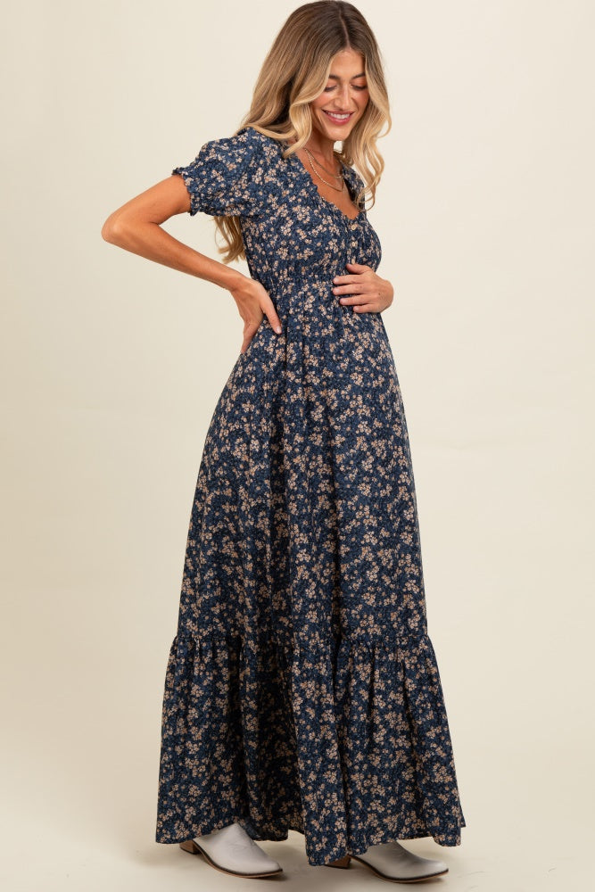 woman wearing a navy blue floral print maternity maxi dress and highlighting her baby bump