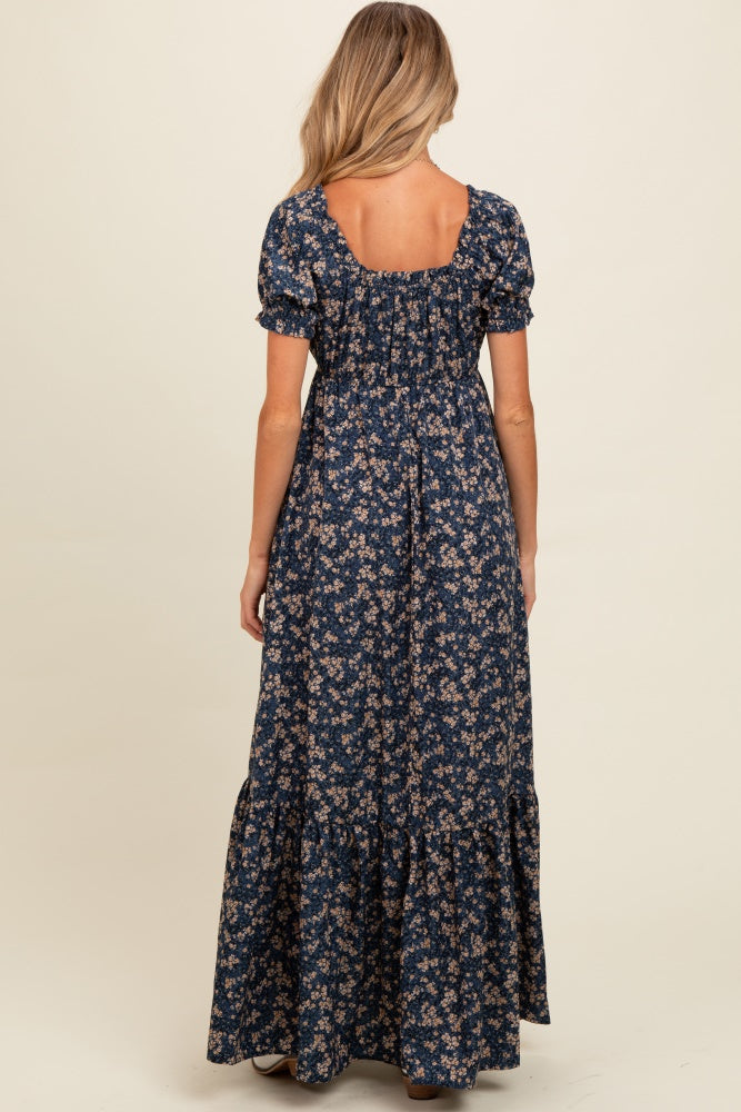 woman wearing a navy blue floral maternity maxi dress with puff sleeves and a ruffled bottom, showing a relaxed fit