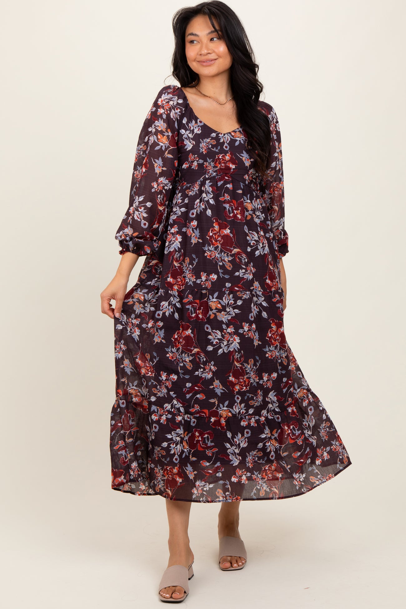 woman wearing a burgundy floral maxi dress with long sleeves and a tiered skirt