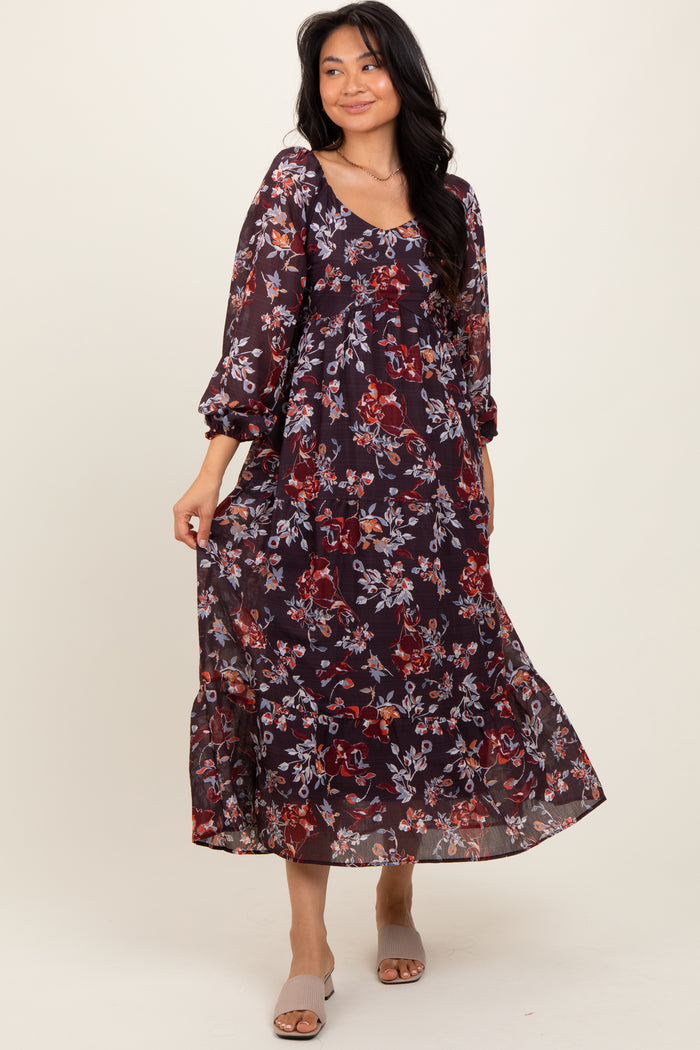 woman wearing a burgundy floral maxi dress with long sleeves and a tiered skirt