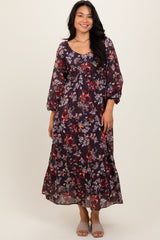 woman wearing a dark floral maxi dress with long sleeves and a ruffled hem, smiling at the camera