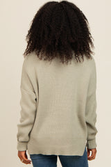 woman wearing a light gray oversized sweater with a crew neckline and ribbed details, viewed from the back