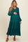 woman wearing a teal maternity maxi dress with long sleeves and tiered ruffle detail, holding her baby bump