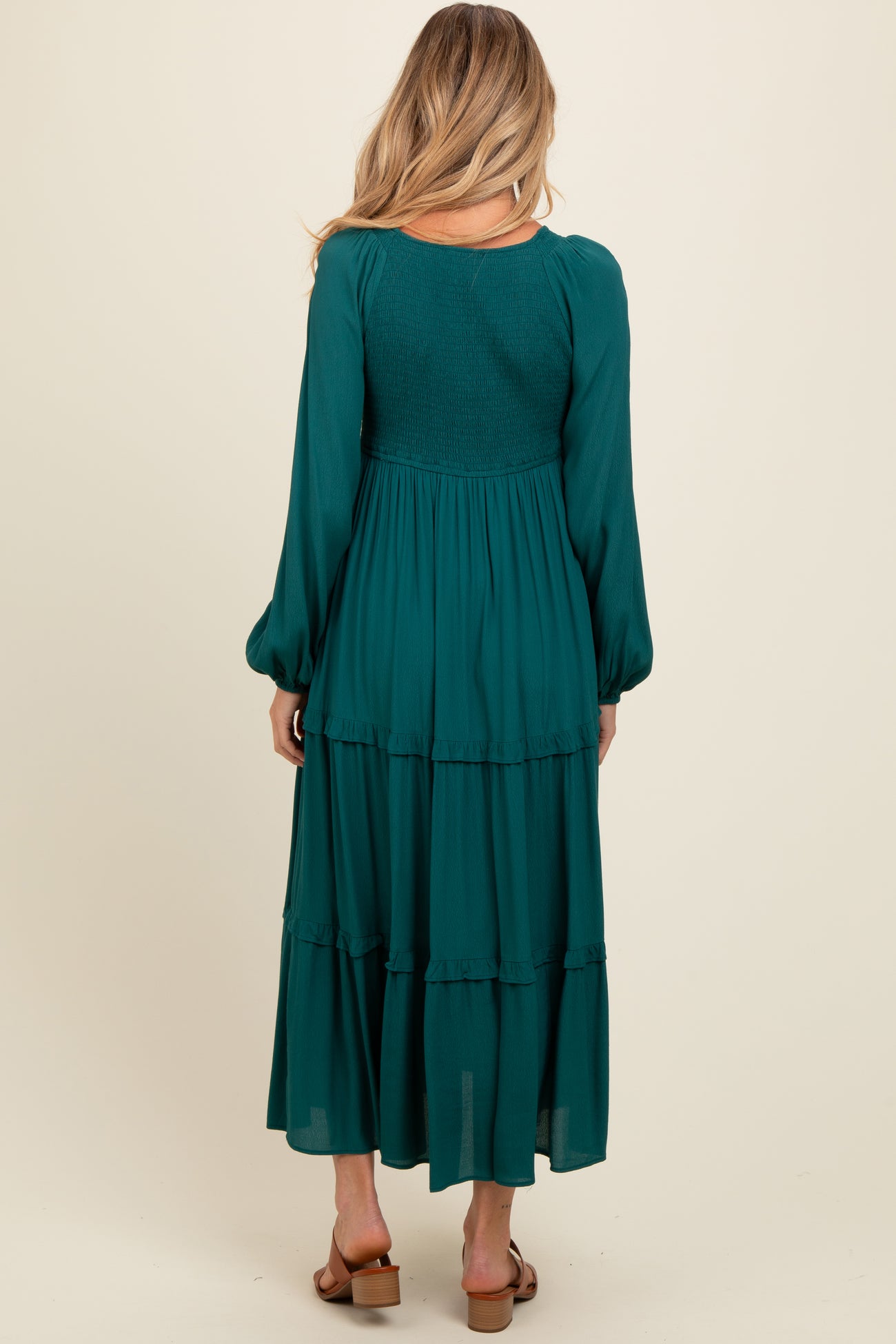 woman wearing a green maternity maxi dress with tiered layers and long sleeves, shown from the back