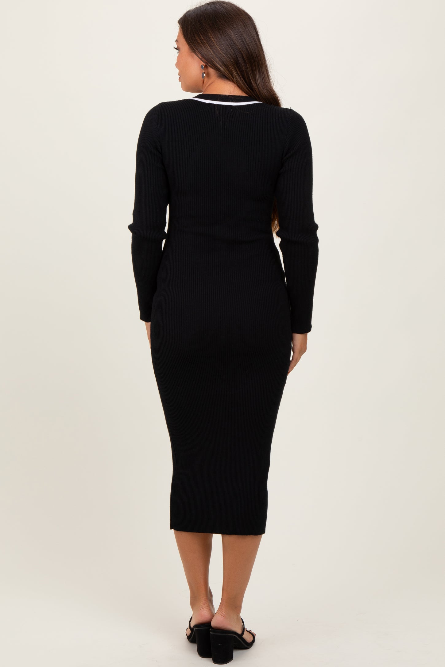 woman wearing a black ribbed maternity dress with long sleeves and a fitted silhouette, showing no baby bump