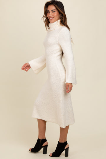 woman wearing a white knit long sleeve turtleneck dress with bell sleeves and a mid-length hem