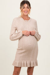 woman wearing a beige cable knit maternity dress with a flared hem and long sleeves, showing her baby bump