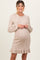 woman wearing a beige cable knit maternity dress with a flared hem and long sleeves, showing her baby bump