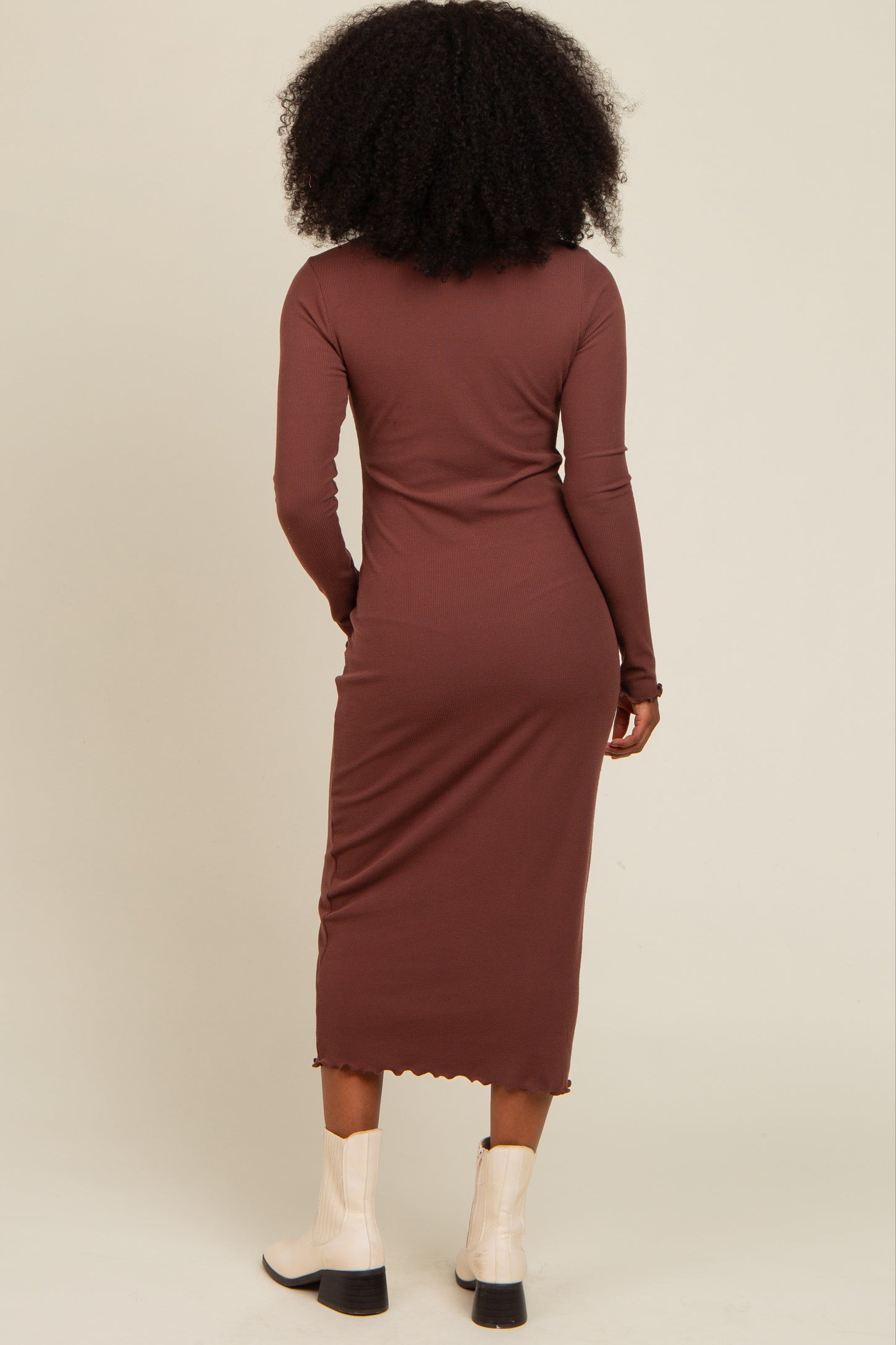 woman wearing a brown long sleeve midi dress with ribbed texture and scalloped hem, viewed from the back