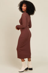 woman wearing a long brown ribbed dress with a scalloped hem and long sleeves, facing away from the camera