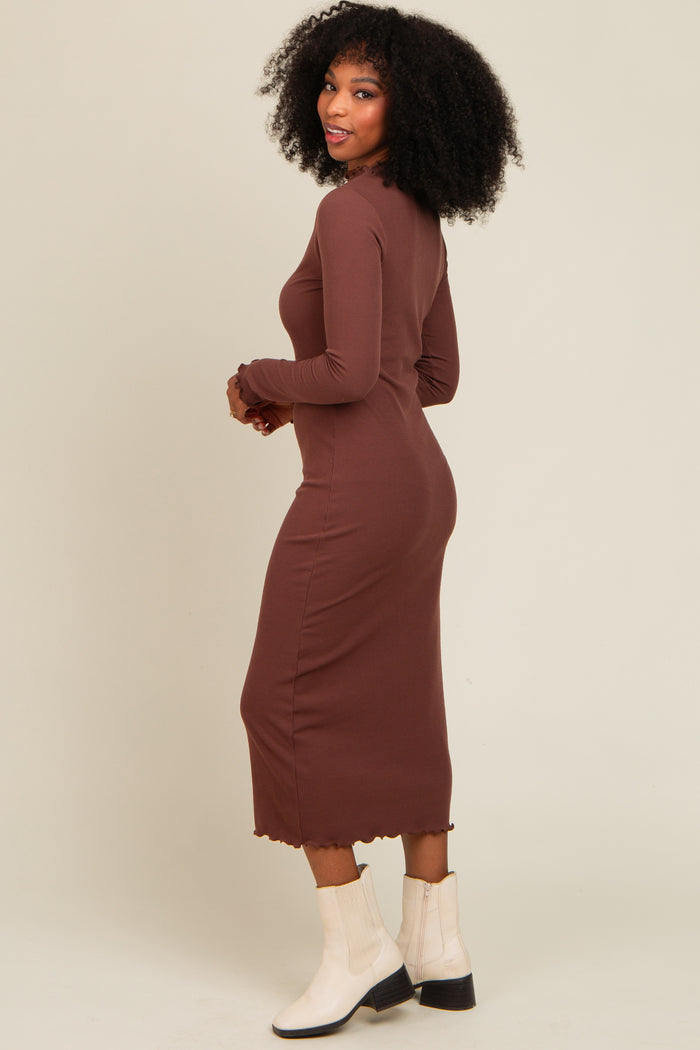 woman wearing a long brown ribbed dress with a scalloped hem and long sleeves, facing away from the camera