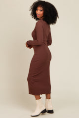 woman wearing a brown long sleeve ribbed midi dress with a scalloped hem and paired with white ankle boots