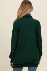 woman wearing a dark green maternity sweater with a slouchy fit and long sleeves, visible from the back