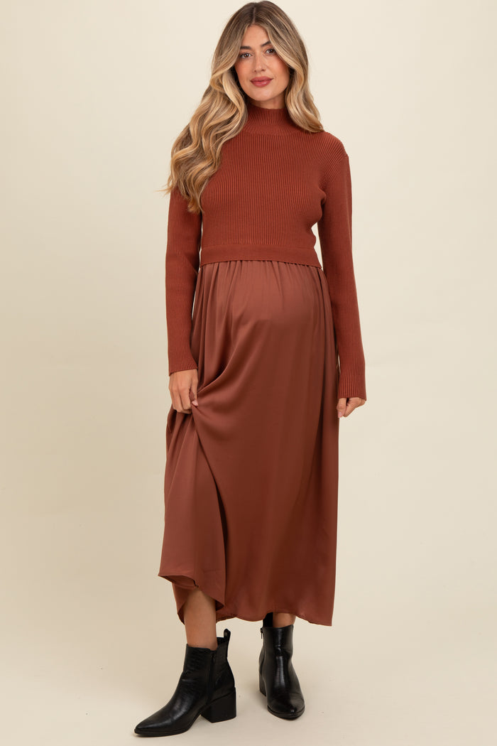 woman wearing a brown ribbed turtleneck maternity top and a flowy brown satin maternity skirt, with a visible baby bump
