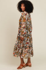 woman wearing a long floral print dress with tiered ruffles and bell sleeves, standing and smiling sideways