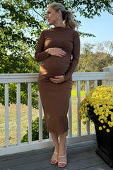 woman wearing a brown long sleeve maternity dress and holding her baby bump while standing on a porch