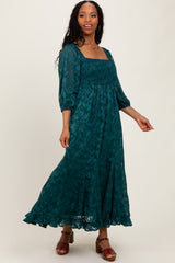 woman wearing a teal floral maxi dress with a square neckline and puff sleeves, posing with one hand on her hip