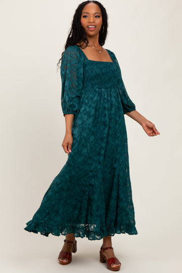woman wearing a teal floral maxi dress with a square neckline and puff sleeves, posing with one hand on her hip