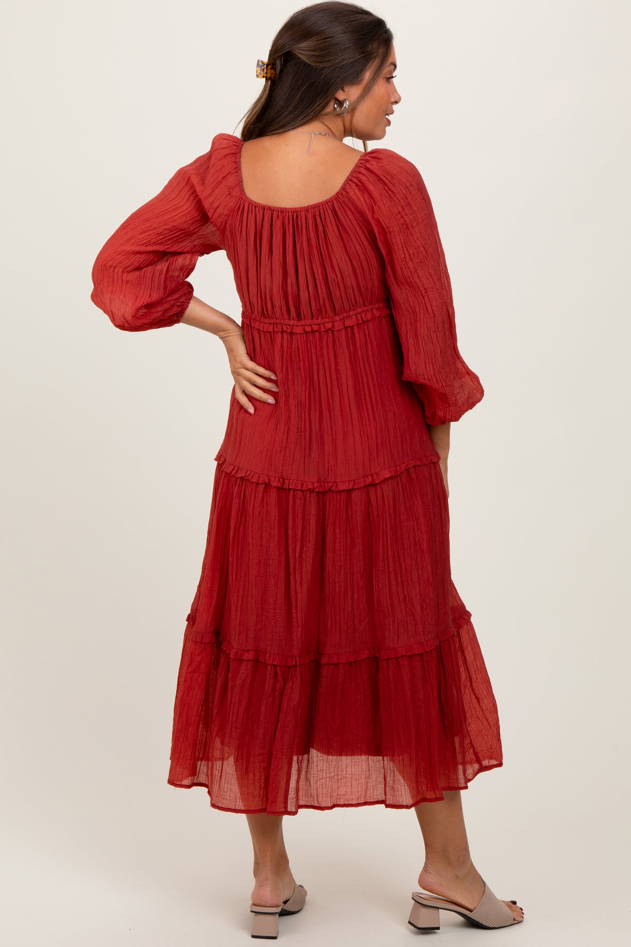 woman wearing a red tiered maternity dress with puffed sleeves and a square back neckline