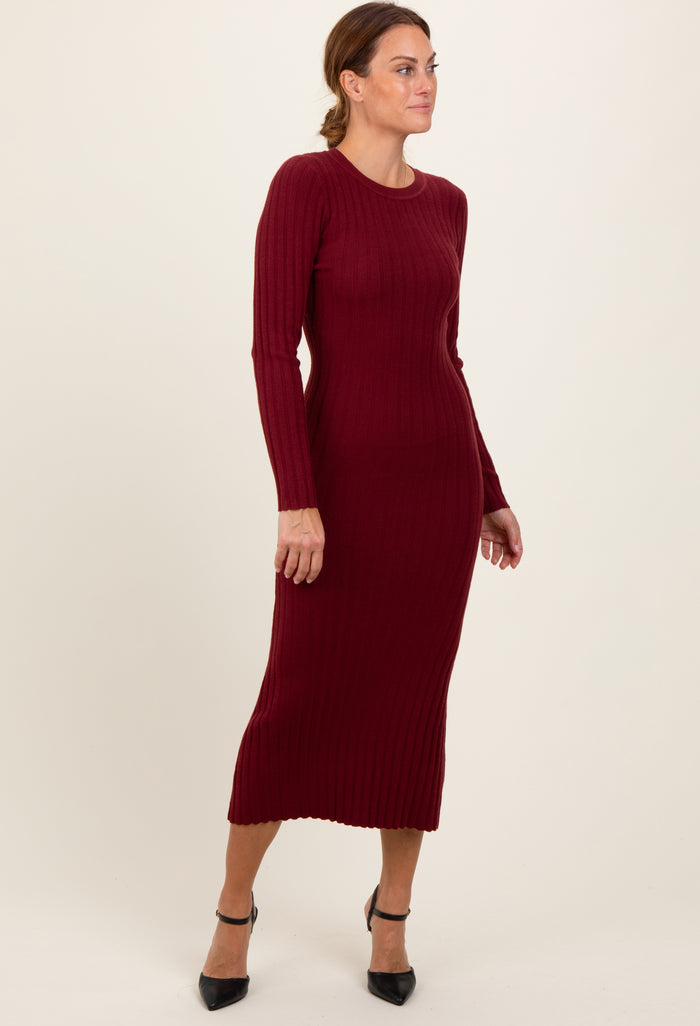 woman wearing a burgundy ribbed long sleeve midi dress with a fitted style and side slit, posing sideways