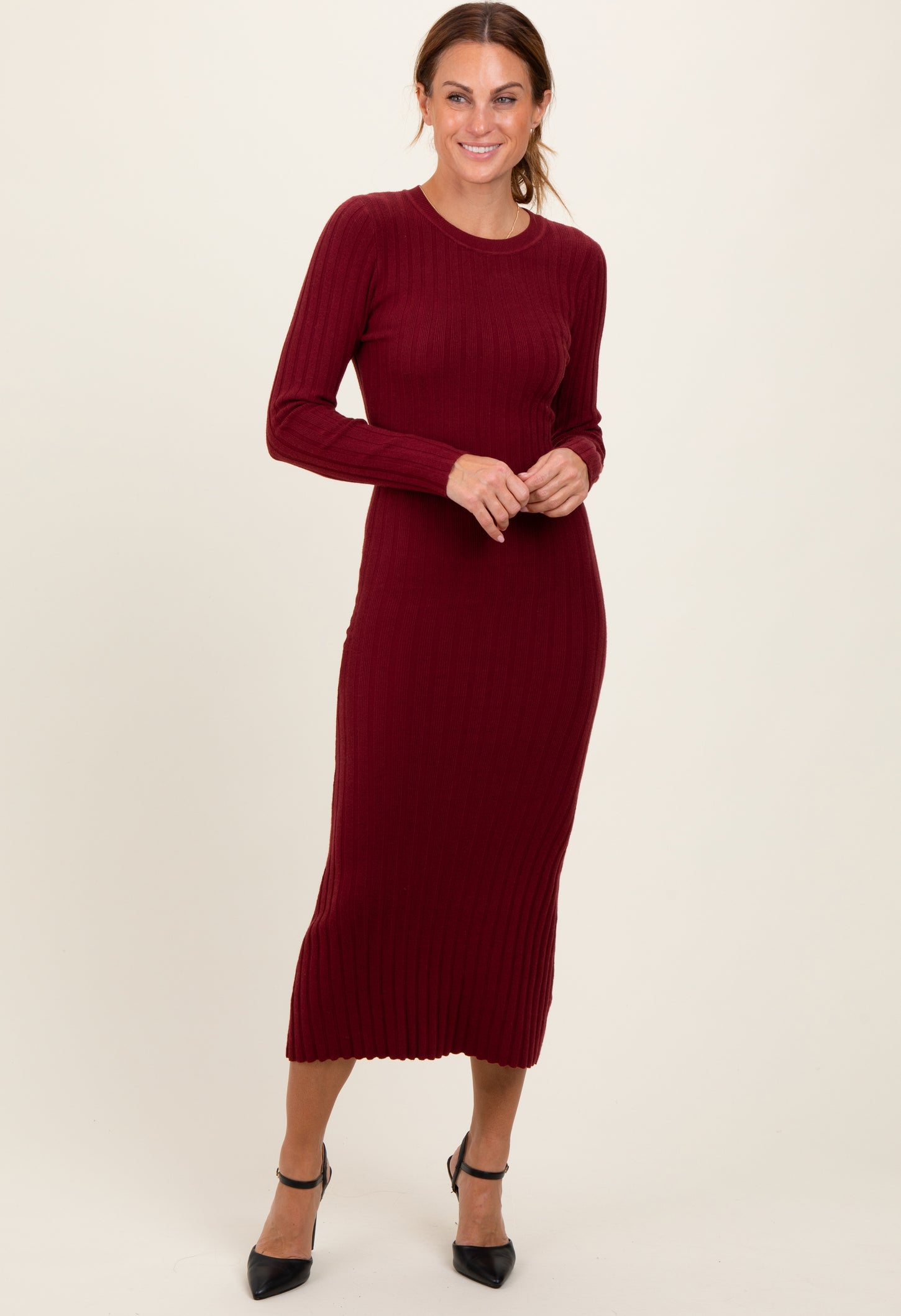 woman wearing a burgundy long sleeve ribbed midi dress and black heeled shoes