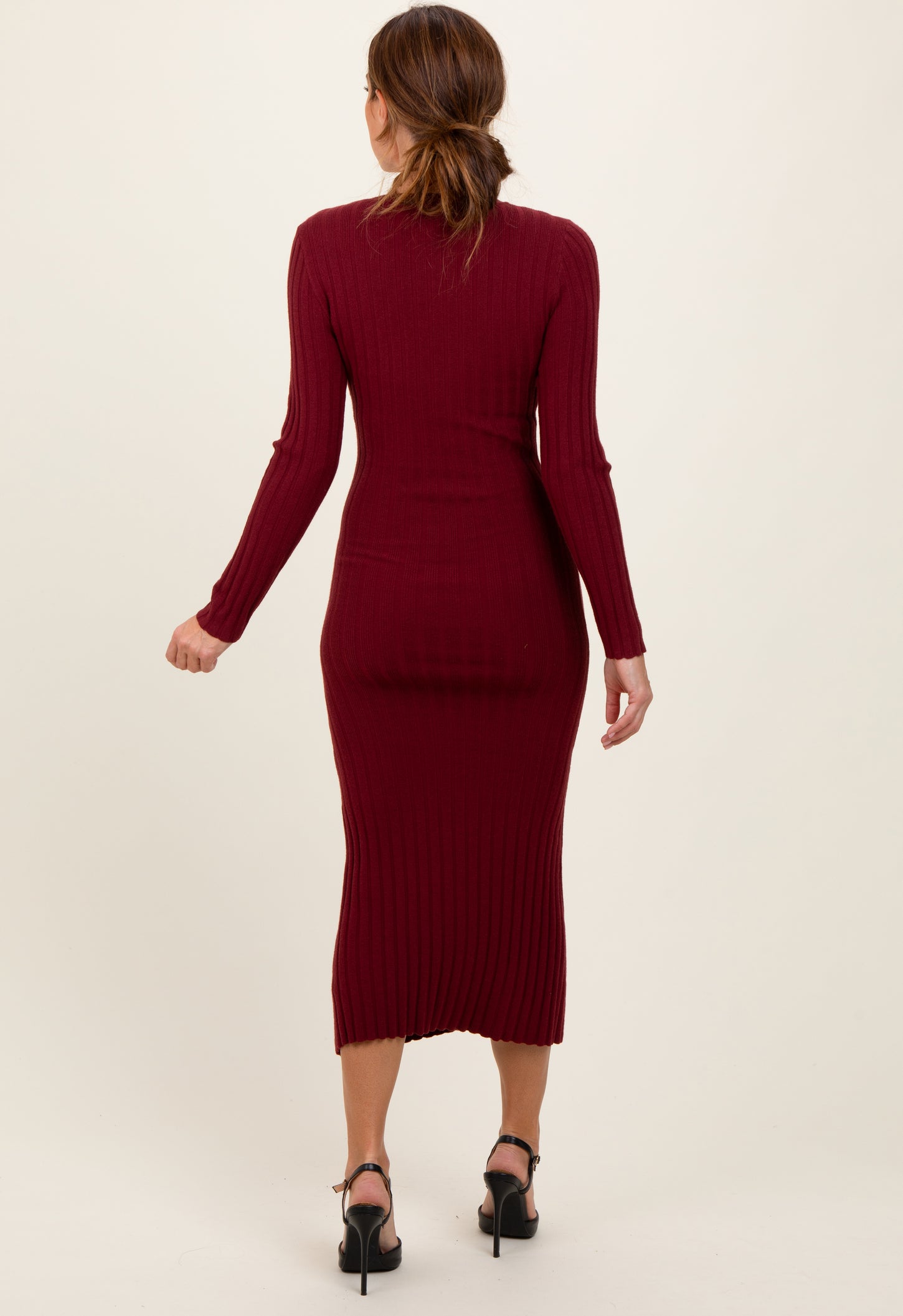 woman wearing a burgundy ribbed midi dress with long sleeves and a fitted silhouette, seen from the back