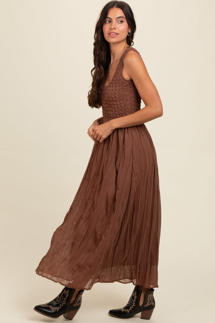 woman wearing a brown maxi dress with a textured bodice and pleated skirt, styled with black western boots